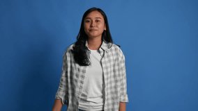 Excited laughing young Asian woman in casual posing isolated on blue background studio. People lifestyle concept. Looking camera screaming with hands gesture near mouth - Powered by Shutterstock - Get 15% off with code: PIKWIZARD15