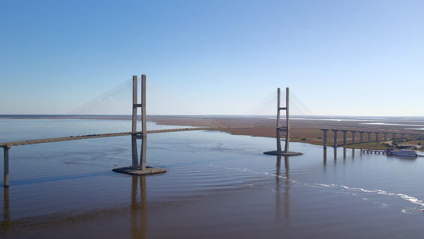 Aerial view of the Sidney Lanier Bridge reflected in the water, cutting through the marshland under a clear sky, Brunswick, Georgia, United States.