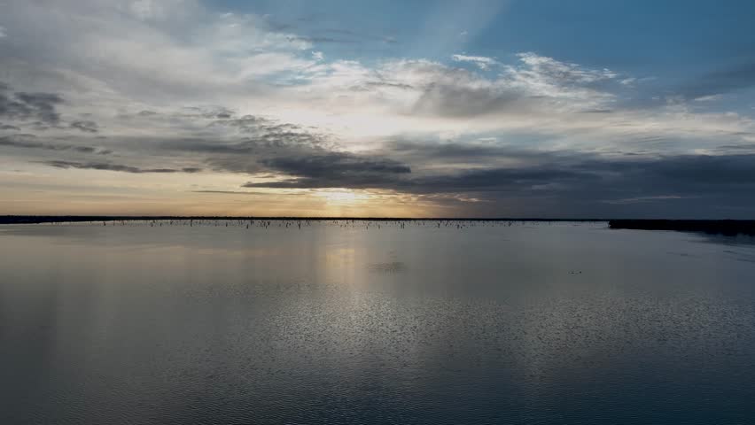 Early morning view of the lake Mulwala and sun hidding behing the clouds. Reflection in the warter and the calm view of the nature.