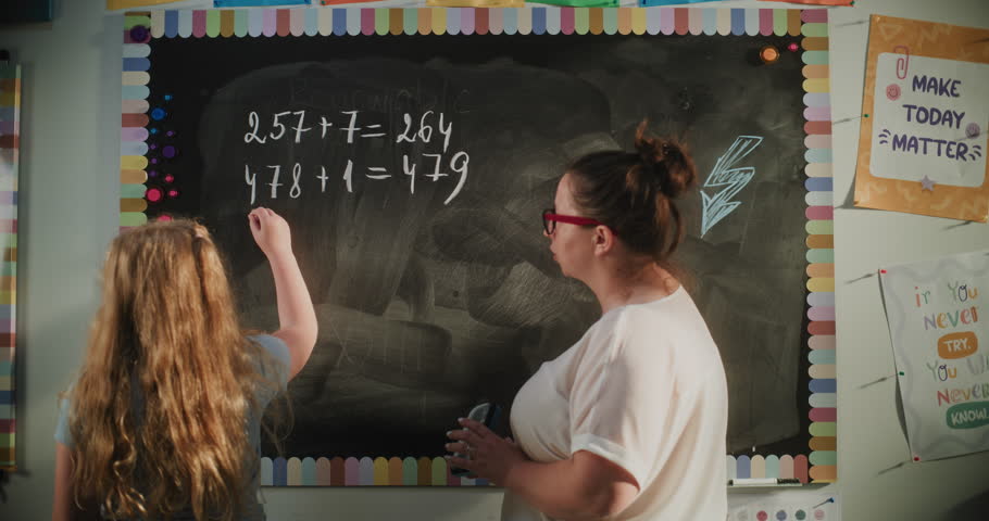 Talented Girl Demonstrating Math Knowledge: Static Shot of Primary School Student Solving Mathematical Problems Writing on the Board with Chalk. Female Teacher Checking Answers, Helping Schoolgirl.