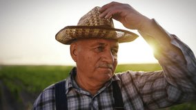 Portrait of charismatic old countryman in beautiful rural landscape in summer. Elderly farmer or agronomist standing alone in farmland, closeup of wrinkled face, person with straw hat for sun protect - Powered by Shutterstock - Get 15% off with code: PIKWIZARD15