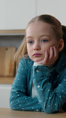 Sad upset pensive thoughtful little offended Caucasian child girl orphan unhappy bad mood lonely kid at home kitchen alone boring stressed daughter sadness family problem domestic violence thinking
