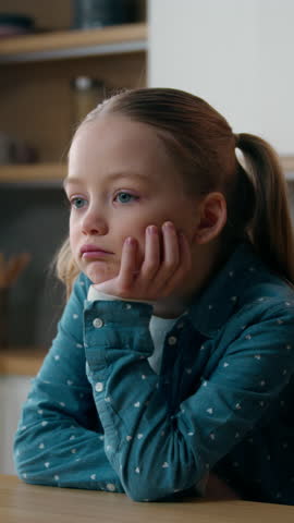 Sad upset pensive thoughtful little offended Caucasian child girl orphan unhappy bad mood lonely kid at home kitchen alone boring stressed daughter sadness family problem domestic violence thinking