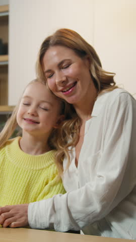 Happy carefree Caucasian family at kitchen smiling mother and little daughter having fun hold hands dancing to music moving dance mom with child girl hug kid hugging cuddling breakfast love bonding