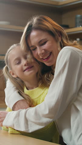 Happy carefree Caucasian family at kitchen smiling mother and little daughter having fun hold hands dancing to music moving dance mom with child girl hug kid hugging cuddling breakfast love bonding