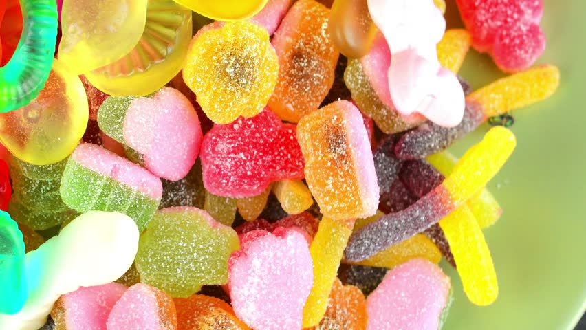 Gummy candies background. Multicolored jelly beans on a rotating background. Macro shot, top view. Concept of sweets and confectionery.