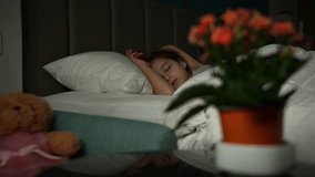 Mother girl care about sleeping daughter child during sleeping in bed. Cute female kid resting and hugging teddy bear toy and mom sitting close to her - Powered by Shutterstock - Get 15% off with code: PIKWIZARD15