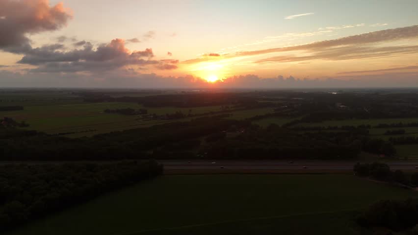 Serene evening landscape in the Dutch countryside. Drone footage of sunset colors fading over dark fields and silhouettes.