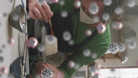 Animation of virus cells over caucasian man with face mask forming pottery. hobby during covid 19 pandemic concept digitally generated video. - Powered by Shutterstock - Get 15% off with code: PIKWIZARD15