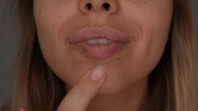 Close-up of a young blonde woman gently moisturizing her dry lips with cream. Focus on lip care, tenderness and beauty routine. Skincare moment - Powered by Shutterstock - Get 15% off with code: PIKWIZARD15