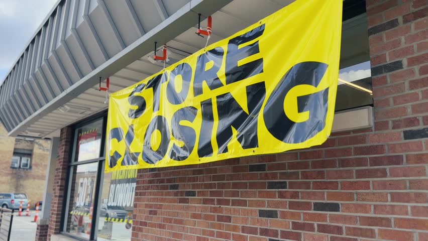 A large yellow and black "Store Closing" banner hangs outside a small-town pharmacy. The sign signals the business's final days, reflecting economic shifts in local retail and community impact. 14729	