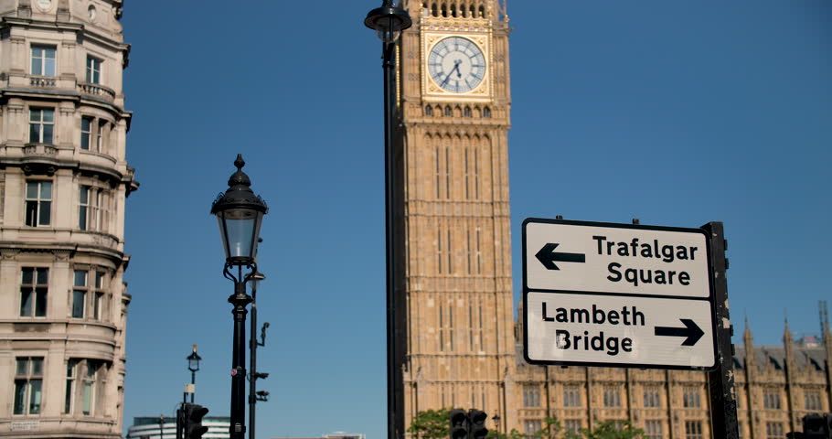 Big Ben, Houses of Parliament and road sign to Trafalgar Square and Lambeth Bridge against a blue sky, summer, London, England