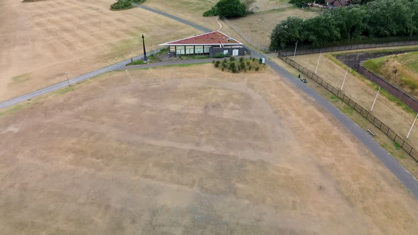 Rotterdam, South Holland, Netherlands - 09.06.2025: Aerial view of a triangular building near a beach, surrounded by grass, a road with parked cars, and walking paths leading to the shoreline.