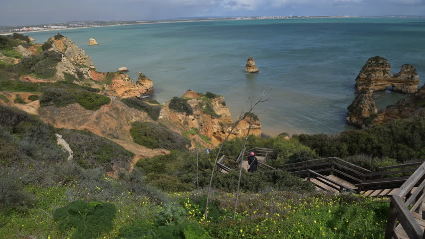 Explore a breathtaking coastal landscape featuring rugged cliffs, calm waters, and lush vegetation. Portugal, Europe.