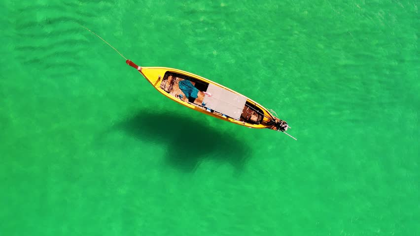 Top down view of traditional wooden fishing boat near scenic Phuket coastline, embodying serene southeast asian maritime tranquility, Thailand