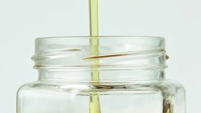 Golden honey dripping slowly into transparent glass jar creating beautiful amber waves and ripples. The thick viscous honey flows steadily forming golden layers - Powered by Shutterstock - Get 15% off with code: PIKWIZARD15