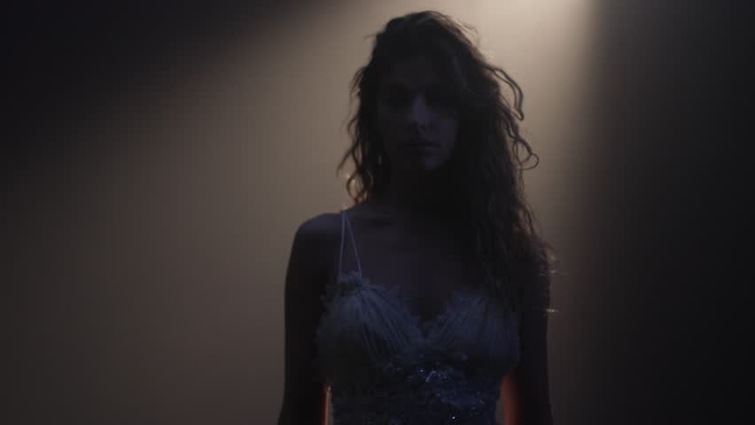 Elegant blonde singer in white dress, bathed in golden spotlight on stage, cinematic atmosphere.