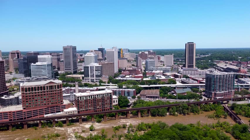 Aerial cinematic video of downtown Richmond, Virginia, featuring the city skyline, high-rises, Manchester Bridge, and the James River on a clear summer day.