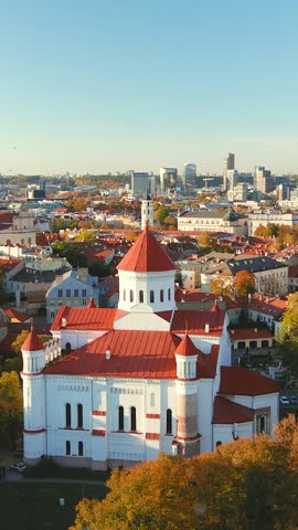 Beautiful vertical aerial Vilnius city Old town panorama in autumn with orange and yellow foliage. Aerial sunny evening view. Cathedral of the Theotokos. Fall city scenery in Vilnius, Lithuania