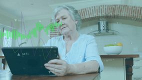 Senior woman raising tablet in kitchen and tapping while browsing stock line graphs for investments. Retirement, digital, analytics, contemplation, technology, home, financial - Powered by Shutterstock - Get 15% off with code: PIKWIZARD15