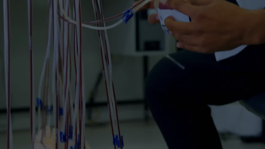 Technician kneeling aligning wires attaching connector while purple swirl showing data flow fading. Electrical, connectivity, industrial, machinery, precision, innovation, stem