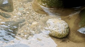 Transparent freshwater ripples calmly across a visible bed of fine sand and brown-toned stones. The natural light enhances the clarity and texture of the underwater scene - Powered by Shutterstock - Get 15% off with code: PIKWIZARD15