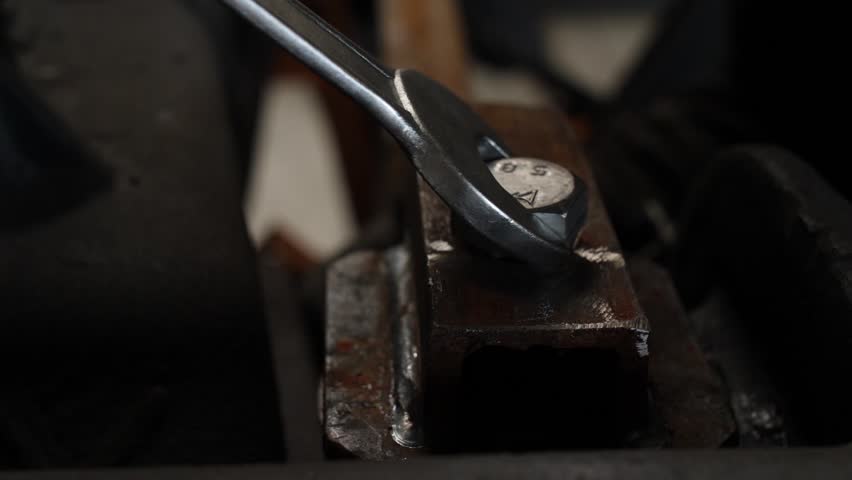 Mechanic uses wrench to tighten bolt on rusted metal part in industrial workshop. Repair, maintenance metal details. Metalworking production manufacturing fabricating on plant, metallurgy factory.