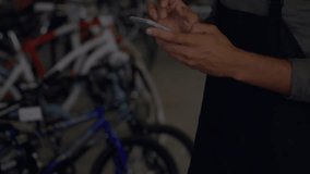 Bike shop employee tapping phone while pulsing sound-wave graphic revealing positive message. Technology, retail, innovation, communication, urban, modern, client service - Powered by Shutterstock - Get 15% off with code: PIKWIZARD15