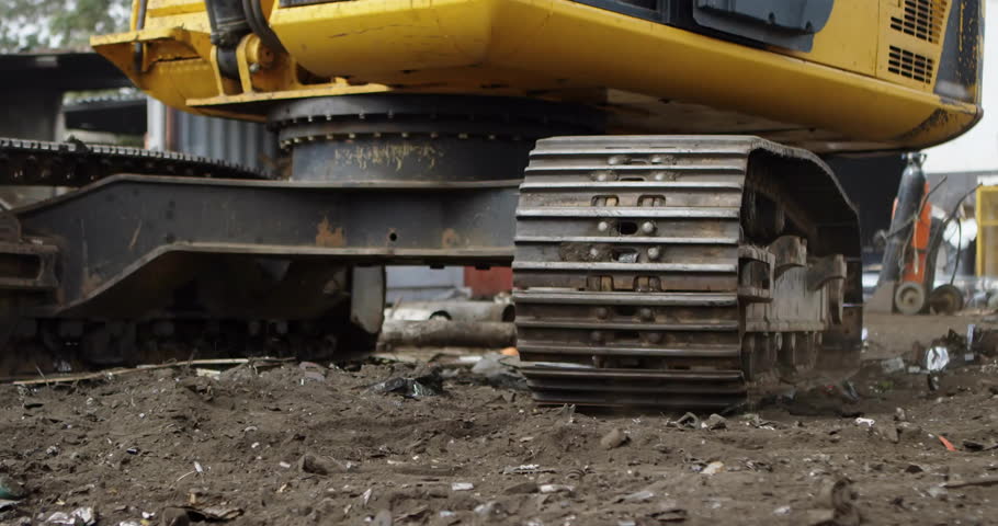Excavator undercarriage idling in mud then wireframe globe fading and rotating showing global build. Industrial machinery, construction site, digital visualization, global connectivity, heavy