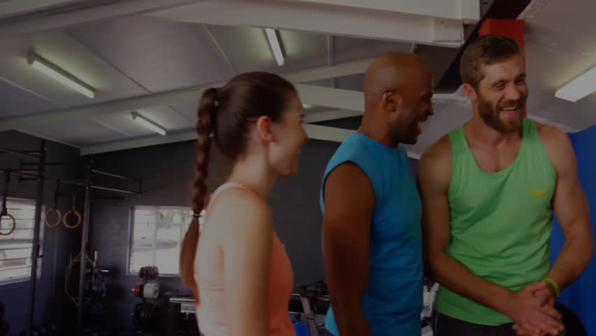 Bearded man shifting stance and inviting new friends in fitness gym near weight bench, laughing. Fitness, camaraderie, teamwork, vitality, community, energy, active