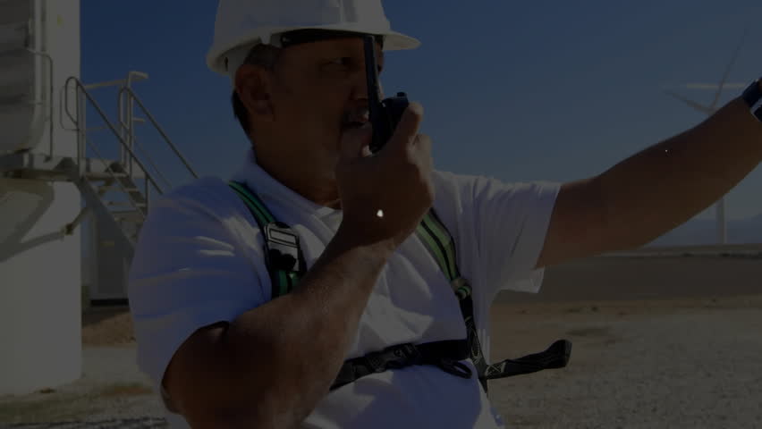 Field engineer speaking into two-way radio, raising hand and building wind farm network overlay. Technology, connectivity, industrial, monitoring, infrastructure, innovation, telecommunications - Powered by Shutterstock - Get 15% off with code: PIKWIZARD15