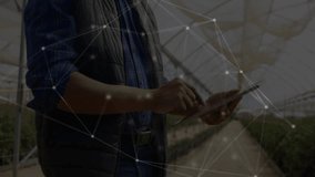 Greenhouse manager tapping tablet in greenhouse and viewing animated data overlay monitoring plants. Tech, innovation, agriculture, smart farming, automation, digital, modern - Powered by Shutterstock - Get 15% off with code: PIKWIZARD15