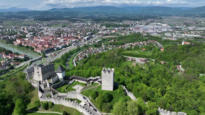 Aerial views of Slovenian landscapes in spring. Drone footage of Celje and its fortress. Historic Celje Castle overlooks vibrant spring townscape, combining medieval legacy and modern life.