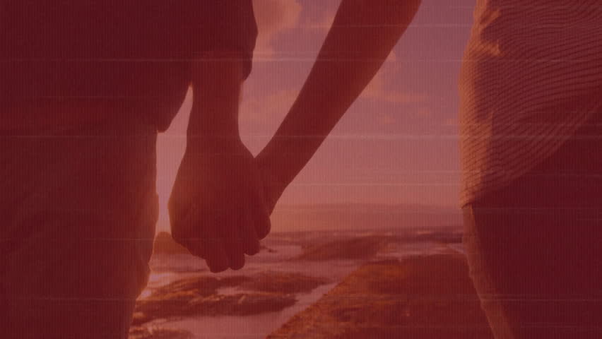 Couple arriving rocky shore and standing holding hands, camera closing on golden sunset for travel. Romance, connection, serenity, horizon, silhouette, nature, warmth