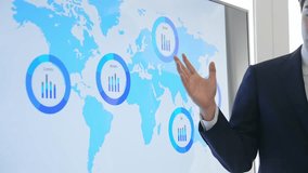 A male business person explaining something using a world map on a large screen monitor - Powered by Shutterstock - Get 15% off with code: PIKWIZARD15