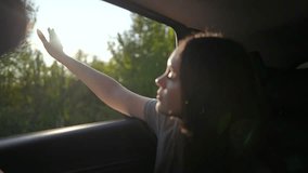 Woman enjoys sunset with hand out car window. Sunlight beams through window as she feels breeze. Carefree road trip at sunset. Woman embraces freedom during golden hour. Joyful car ride evening light. - Powered by Shutterstock - Get 15% off with code: PIKWIZARD15