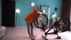 Young woman in eyeglasses and orange shirt repairing bicycle at home. Bike repair and maintenance - Powered by Shutterstock - Get 15% off with code: PIKWIZARD15