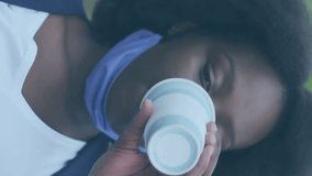 Animation of social media icons over african american woman with face mask srinking coffee. Global covid 19 pandemic, social media, and digital interface concept digitally generated video. - Powered by Shutterstock - Get 15% off with code: PIKWIZARD15