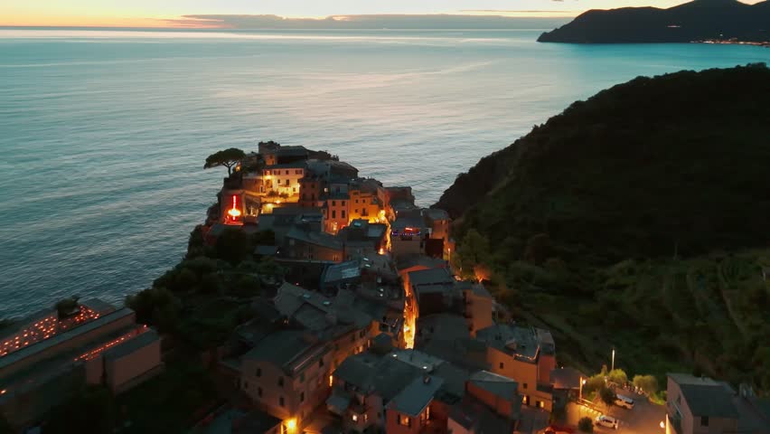 Aerial view of the picturesque resort town of Corniglia at night in the famous Cinque Terre, Liguria, Italy. Historic village with colorful buildings nestled between cliffs and the Ligurian Sea. 