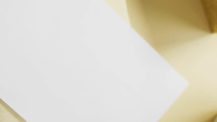 Golden confetti animation over blank card and envelope on festive background. Celebration, party, holiday, decoration