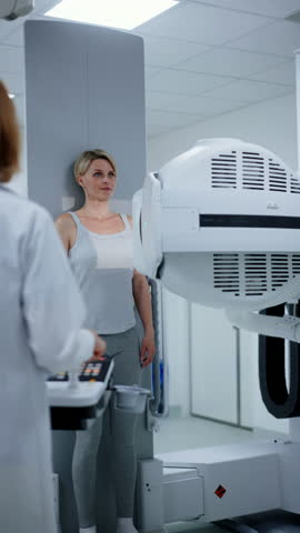 Female patient undergoing dynamic X-ray scan using tilting fluoroscopy wall unit.