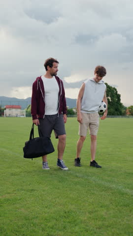 Father and son playing football on a field.