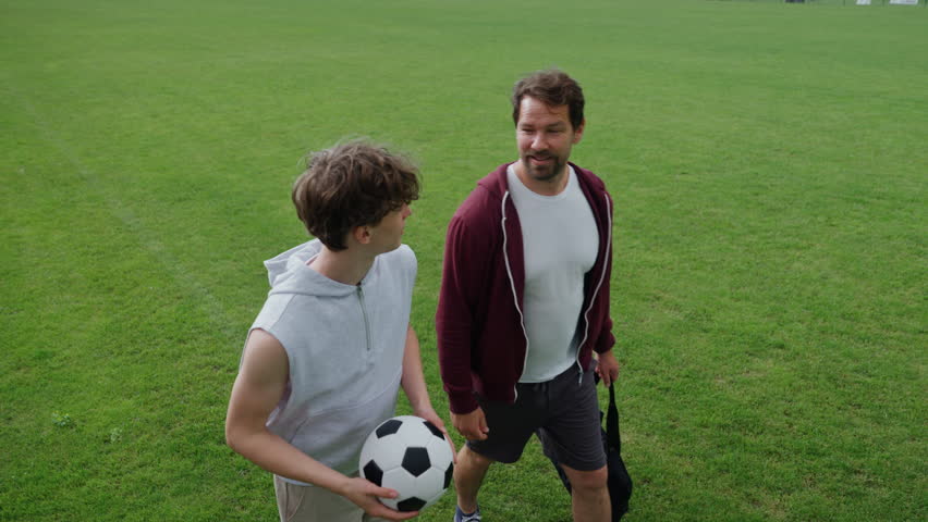 Father and son playing football on a field.