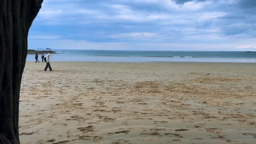 View on at people walking on the Plage de l’Eventail sandy beach of the English Channel at low tide in Saint Malo, Brittany, France.