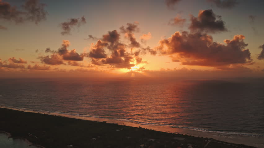 French Polynesia, Rangiroa island: Aerial view stunning golden sunset over Rangiroa, French Polynesia, sunbeams cloudy sky over ocean and land. Wild nature travel landscape. Drone flight footage