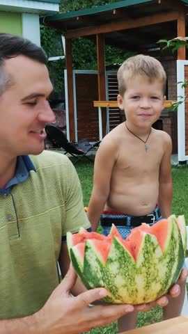 Father with a four-year-old son cut a watermelon and eat it, have fun, a boy likes watermelon very much. sweet watermelon for lunch with family.