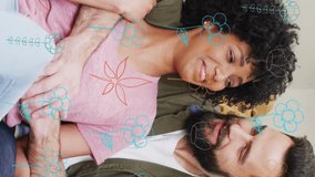 Animation of flowers over happy diverse couple talking and embracing at home. Relationship, love, communication, spring, and lifestyle concept digitally generated video. - Powered by Shutterstock - Get 15% off with code: PIKWIZARD15