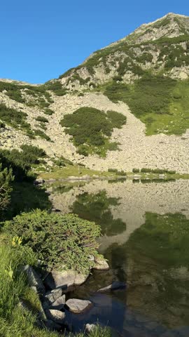 Sunny panoramic view of Muratovo Lake with mountain reflections in Pirin Mountains, Bulgaria in July 2025
