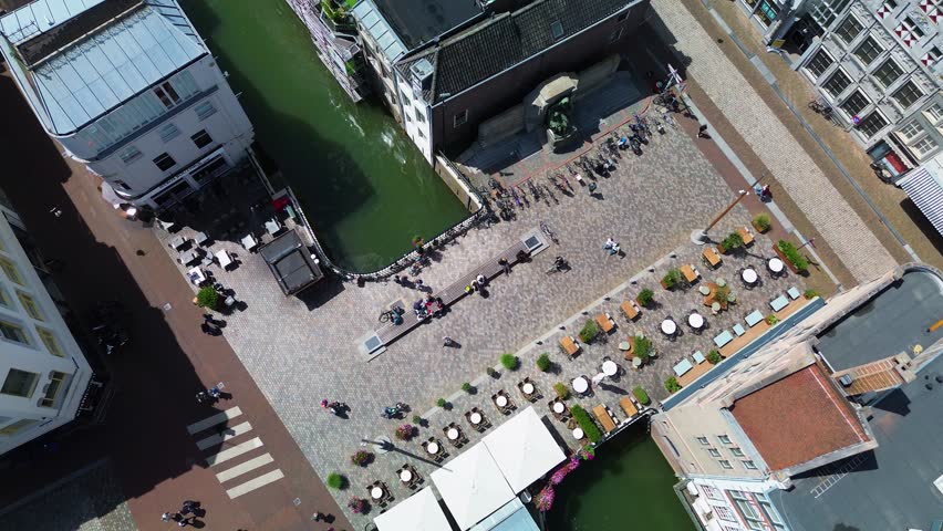 Utrecht, Utrecht region, Netherlands - 09.06.2025: Aerial view of a charming European city with canals, cobblestone streets, outdoor cafes, and historic buildings. People walk and relax lively public