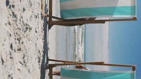 Animation of white flowers over diverse couple in deckchairs holding hands on beach. holiday, love and leisure time concept digitally generated video. - Powered by Shutterstock - Get 15% off with code: PIKWIZARD15